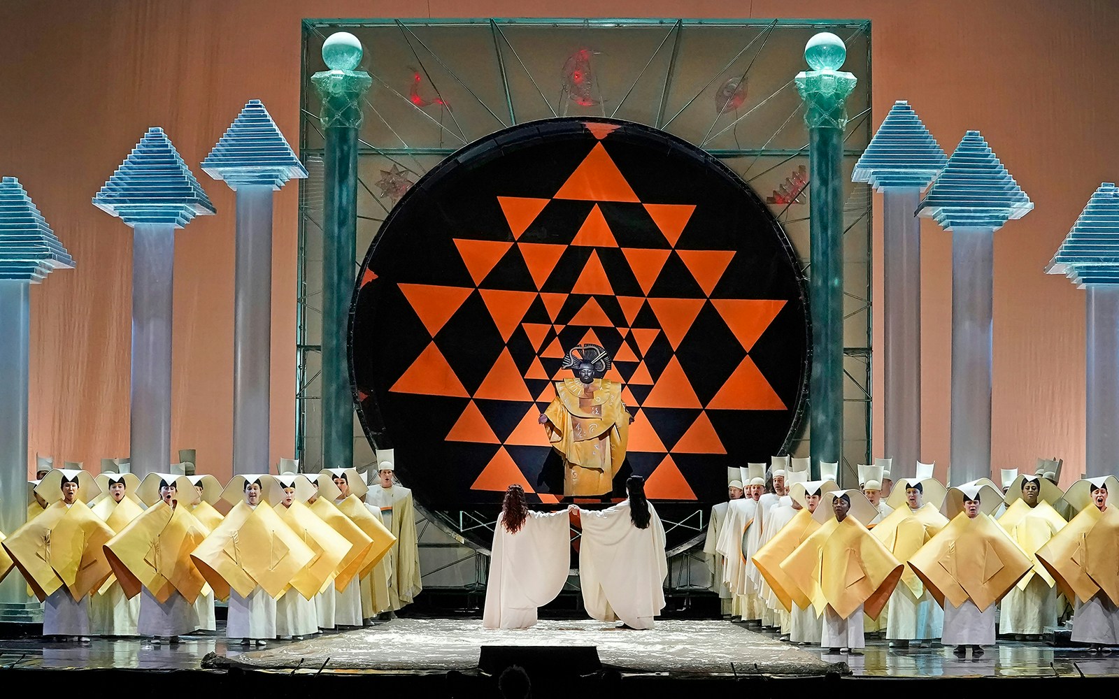 Opera performance of The Magic Flute with singers in geometric costumes on stage.