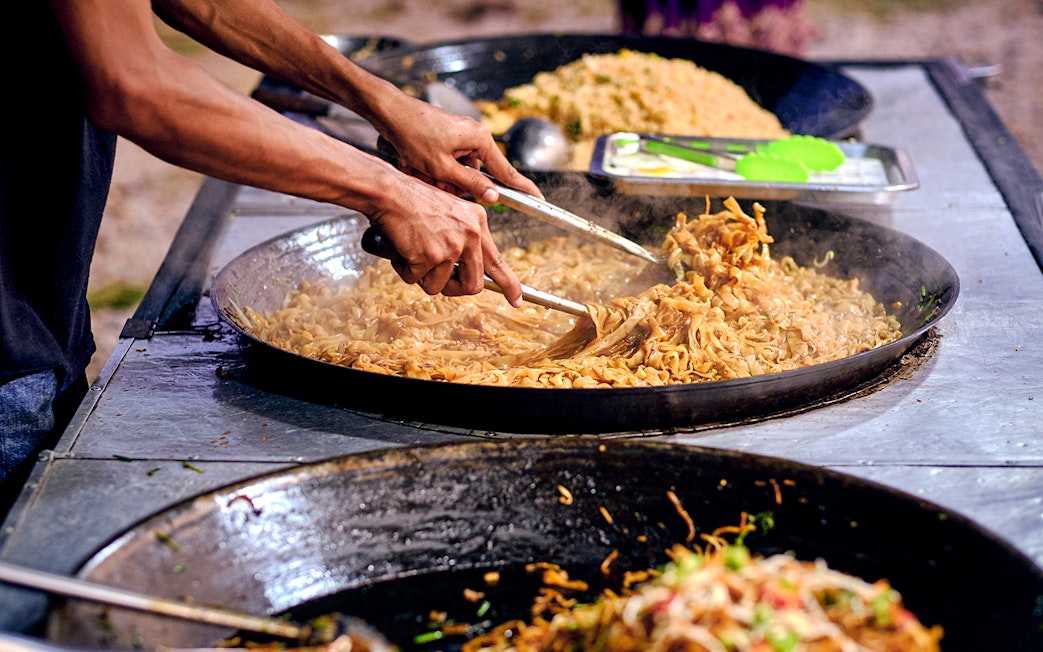 Langkawi street food vendor cooking noodles in a large pan.