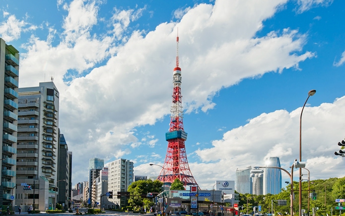 Tokyo Tower surrounded by city buildings under a blue sky in Tokyo.
