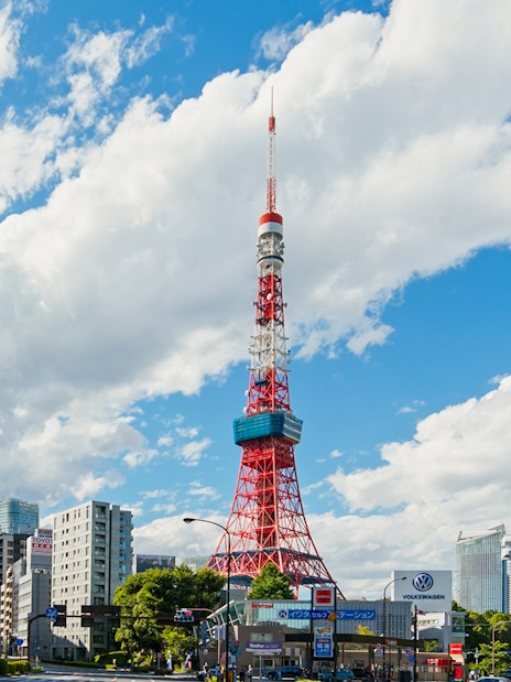 Tokyo Tower surrounded by city buildings under a blue sky in Tokyo.