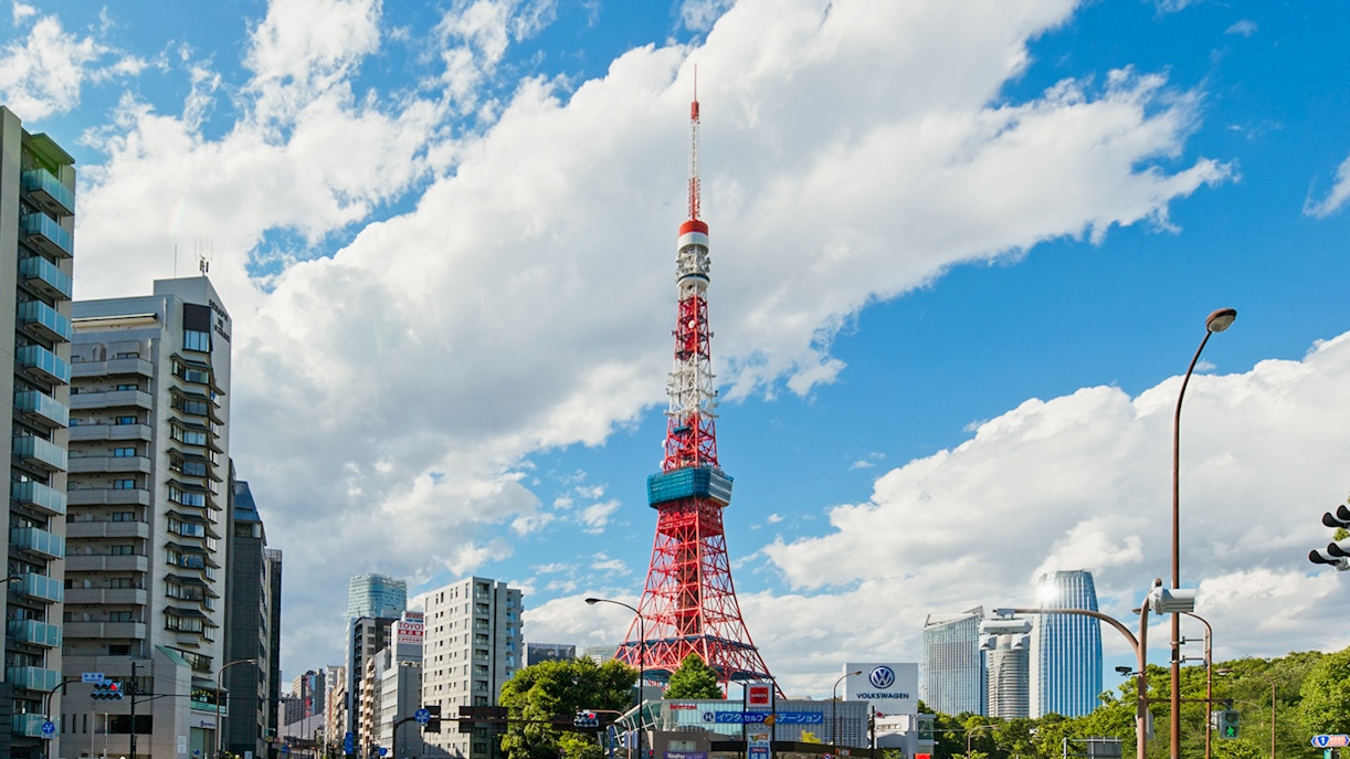 Tokyo Tower surrounded by city buildings under a blue sky in Tokyo.