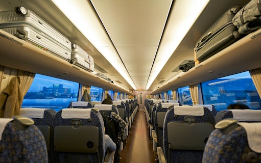 JR West Thunderbird train interior with central aisle and overhead luggage racks.