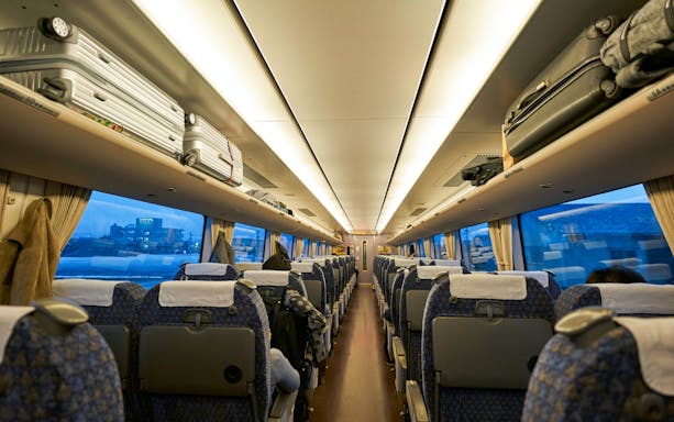 JR West Thunderbird train interior with central aisle and overhead luggage racks.