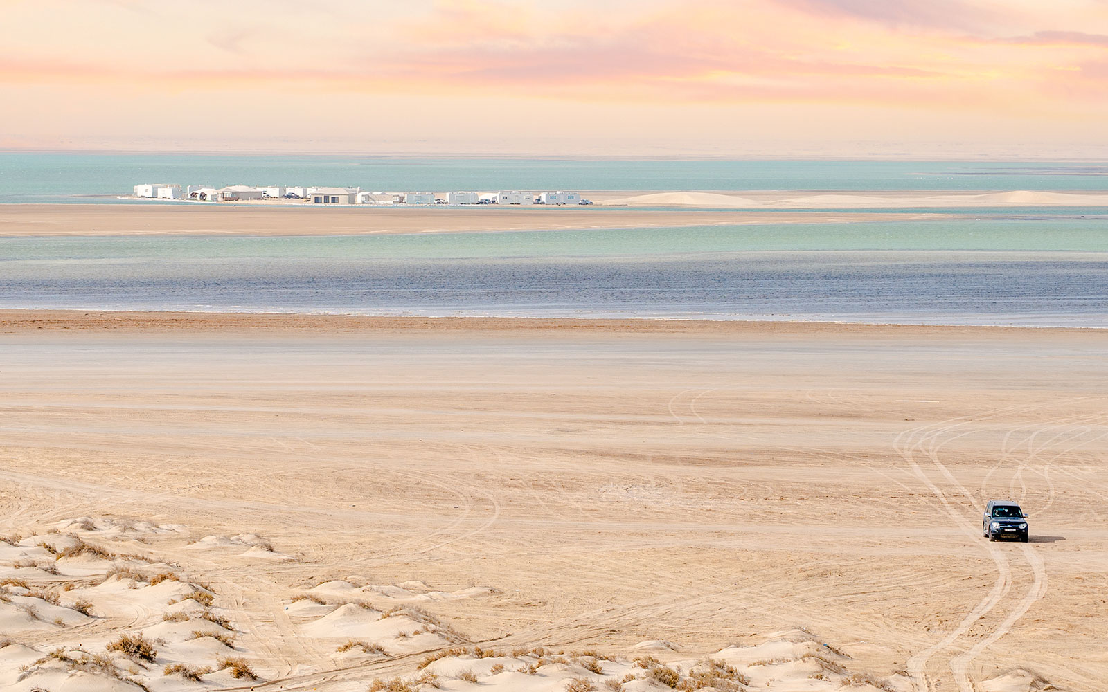Inland sea beach view in Qatar from dune with vehicle tracks.