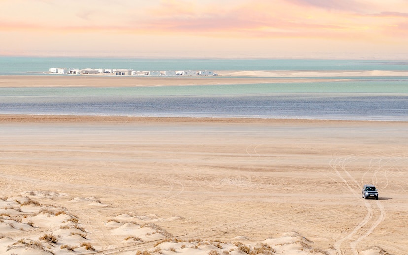 Inland sea beach view in Qatar from dune with vehicle tracks.