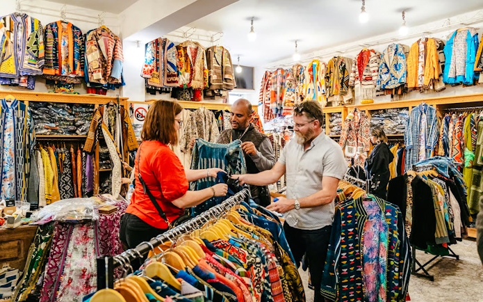 Shoppers exploring colorful garments in a Marrakech souk during a private shopping tour.