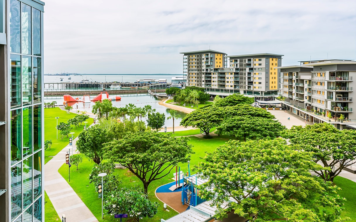 Darwin waterfront view with lush park, modern buildings, and harbor, seen from Big Bus tour route.