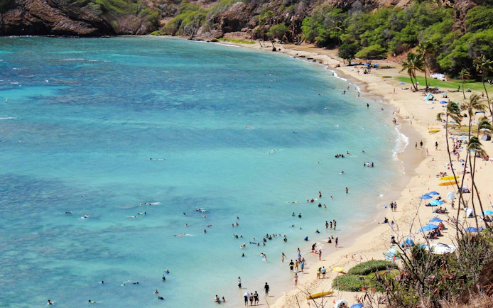Visitors swimming and relaxing on the beach at Hanauma Bay Nature Preserve, Oahu.