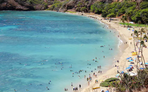 Visitors swimming and relaxing on the beach at Hanauma Bay Nature Preserve, Oahu.