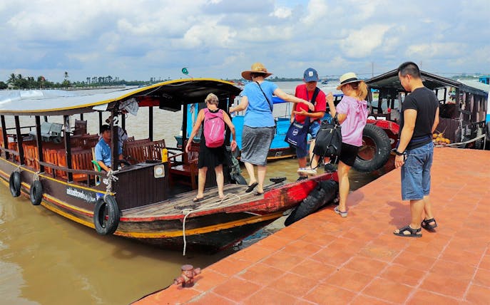 Tourists boarding a boat for a Mekong Delta full day tour in Vietnam.