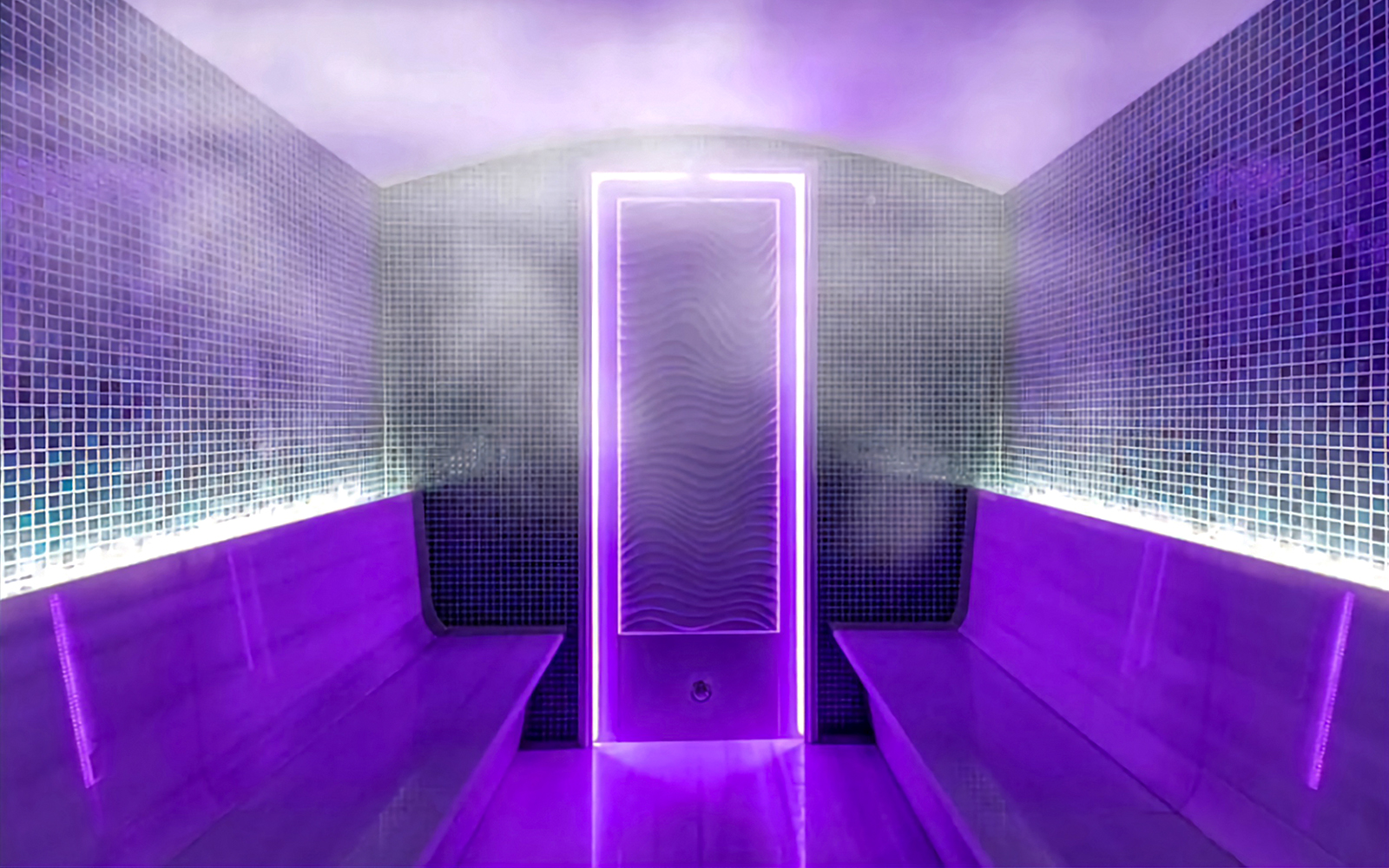 Interior of a private Turkish bath with purple lighting and steam.