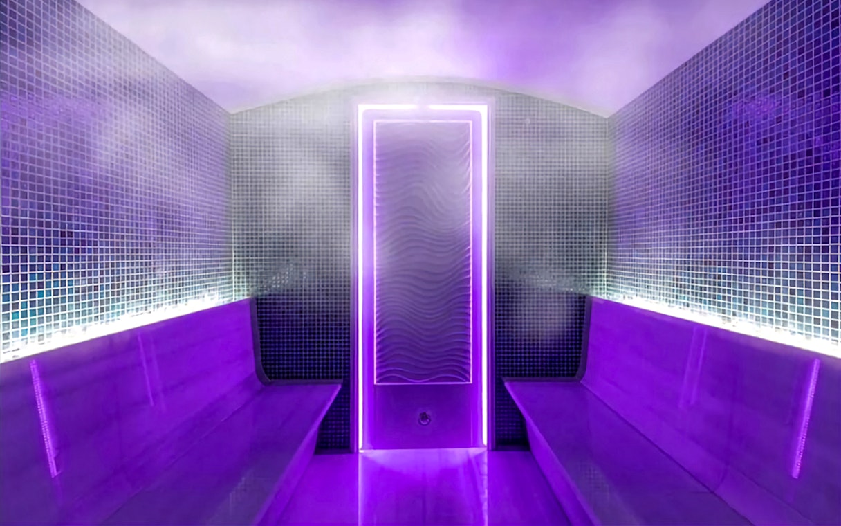 Interior of a private Turkish bath with purple lighting and steam.