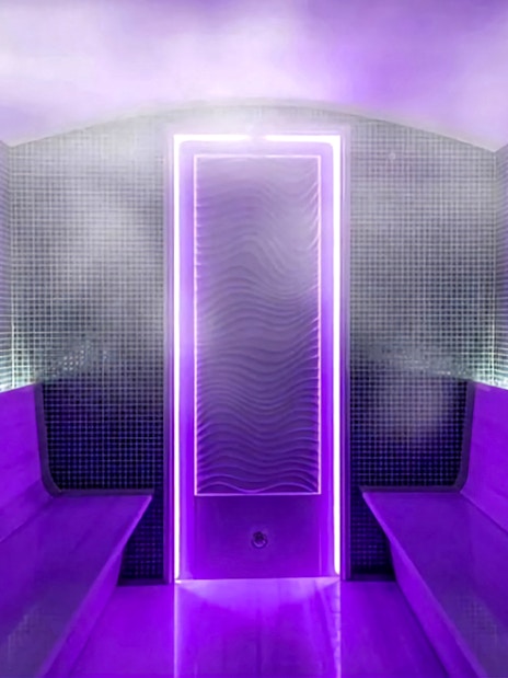 Interior of a private Turkish bath with purple lighting and steam.