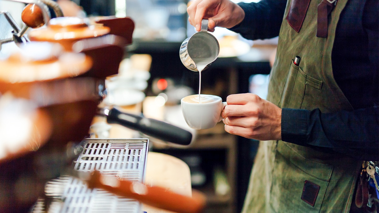 Barista preparing espresso at a bustling coffee shop in Italy.