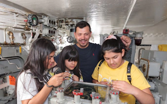 Visitors exploring navigation equipment on Battleship IOWA guided gun tour.