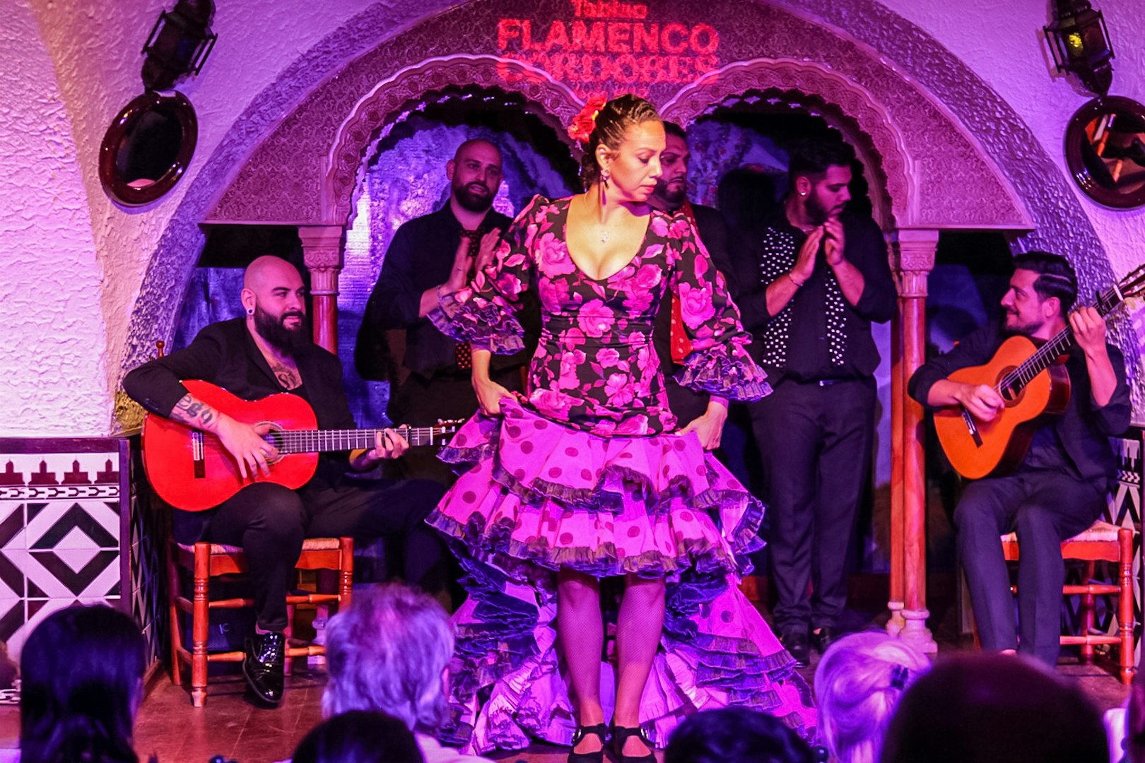 Flamenco dancer performing at Tablao Cordobes with musicians playing guitar in the background.