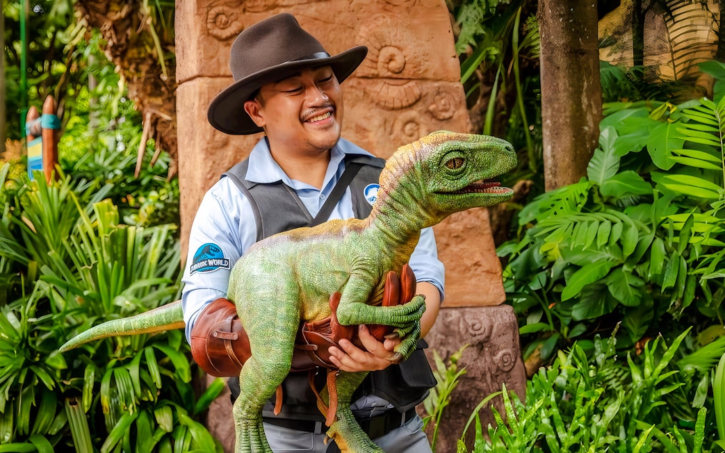 Baby dinosaur with handler Kai in a park, engaging kids and families.