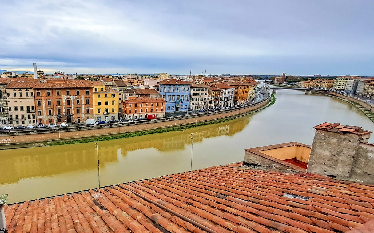 Rooftop view of Pisa's colorful riverside buildings along the Arno River during a guided walking tour.