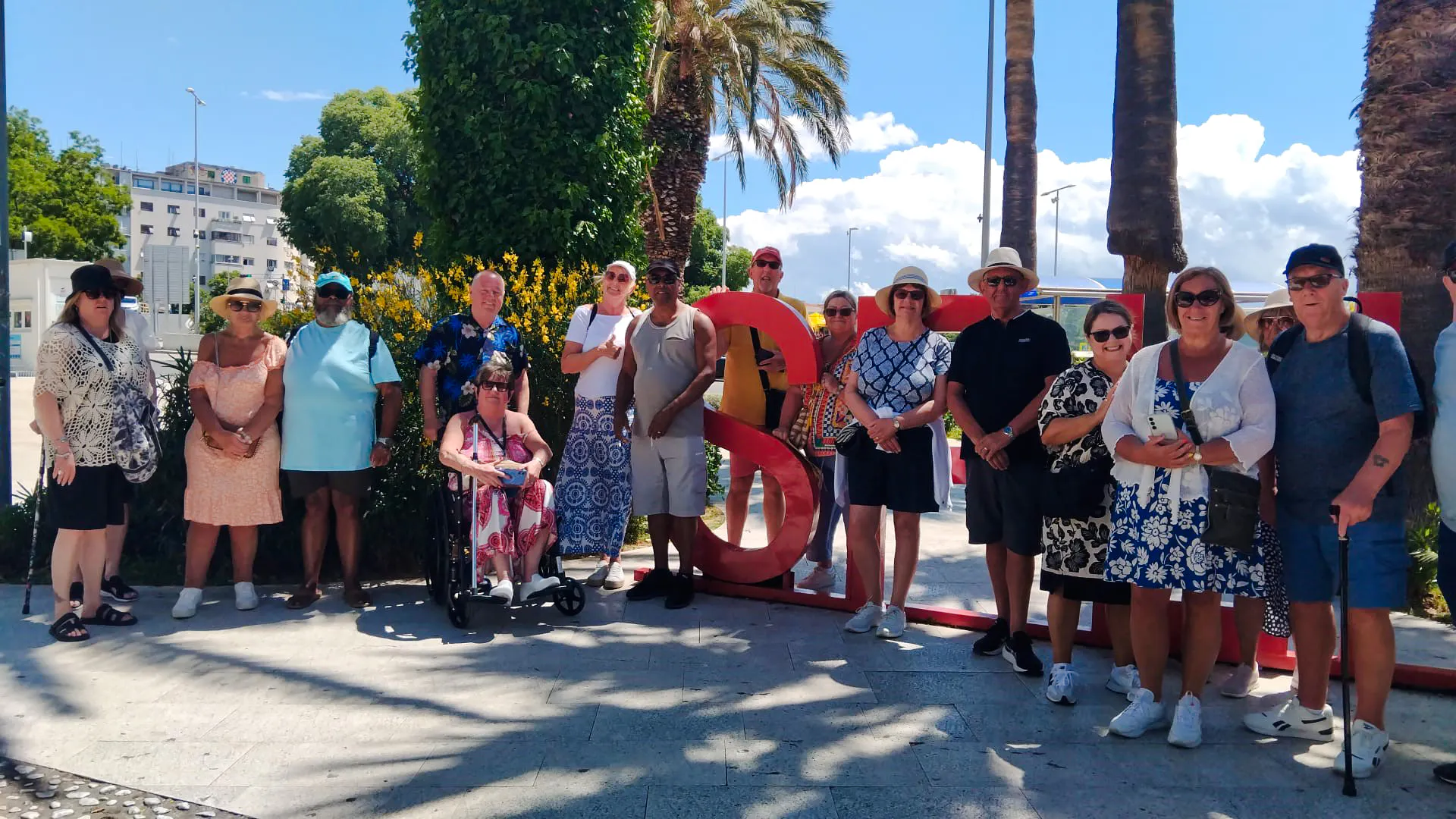 Group of tourists posing by a large red "S" sculpture during Split City Tour, Croatia.