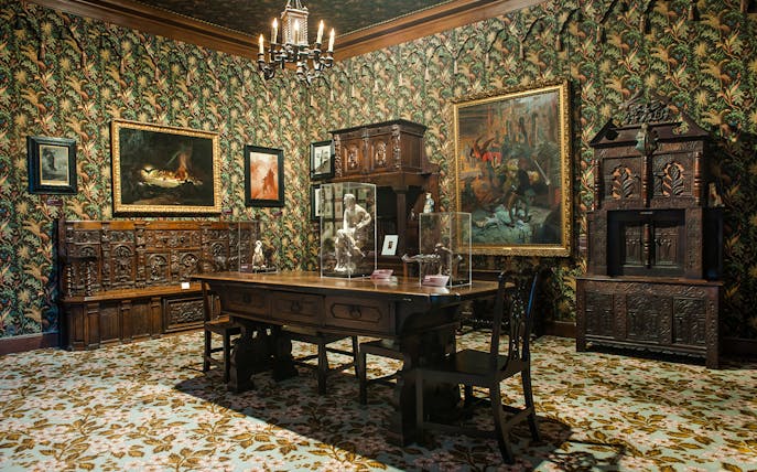 Interior of The Victor Hugo House in Paris, featuring ornate wooden furniture and framed artwork.
