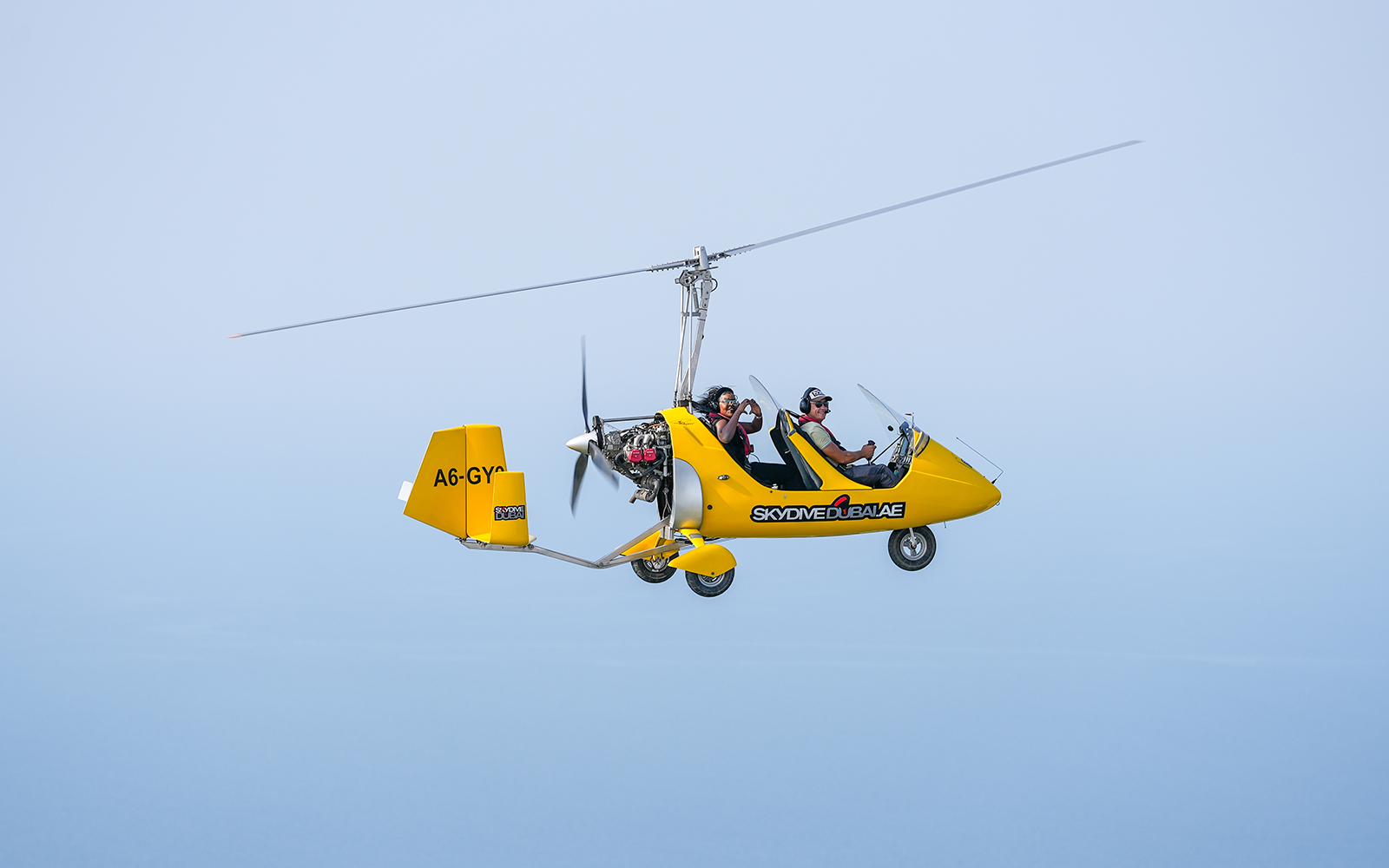 Gyrocopter flying over Skydive Dubai Palm Drop Zone with two passengers.