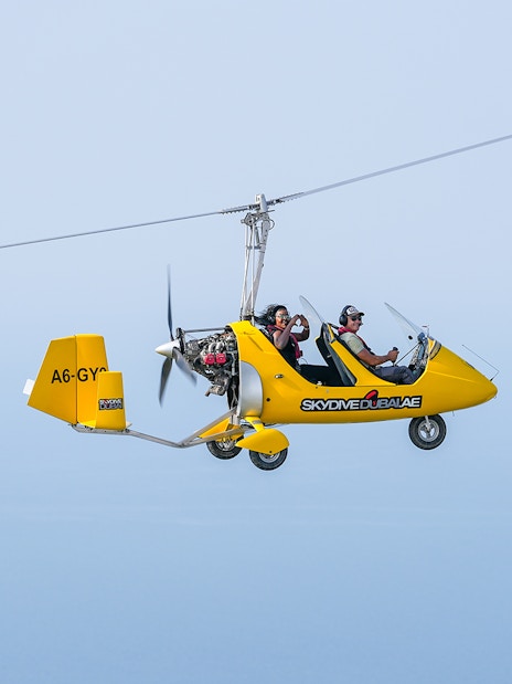 Gyrocopter flying over Skydive Dubai Palm Drop Zone with two passengers.