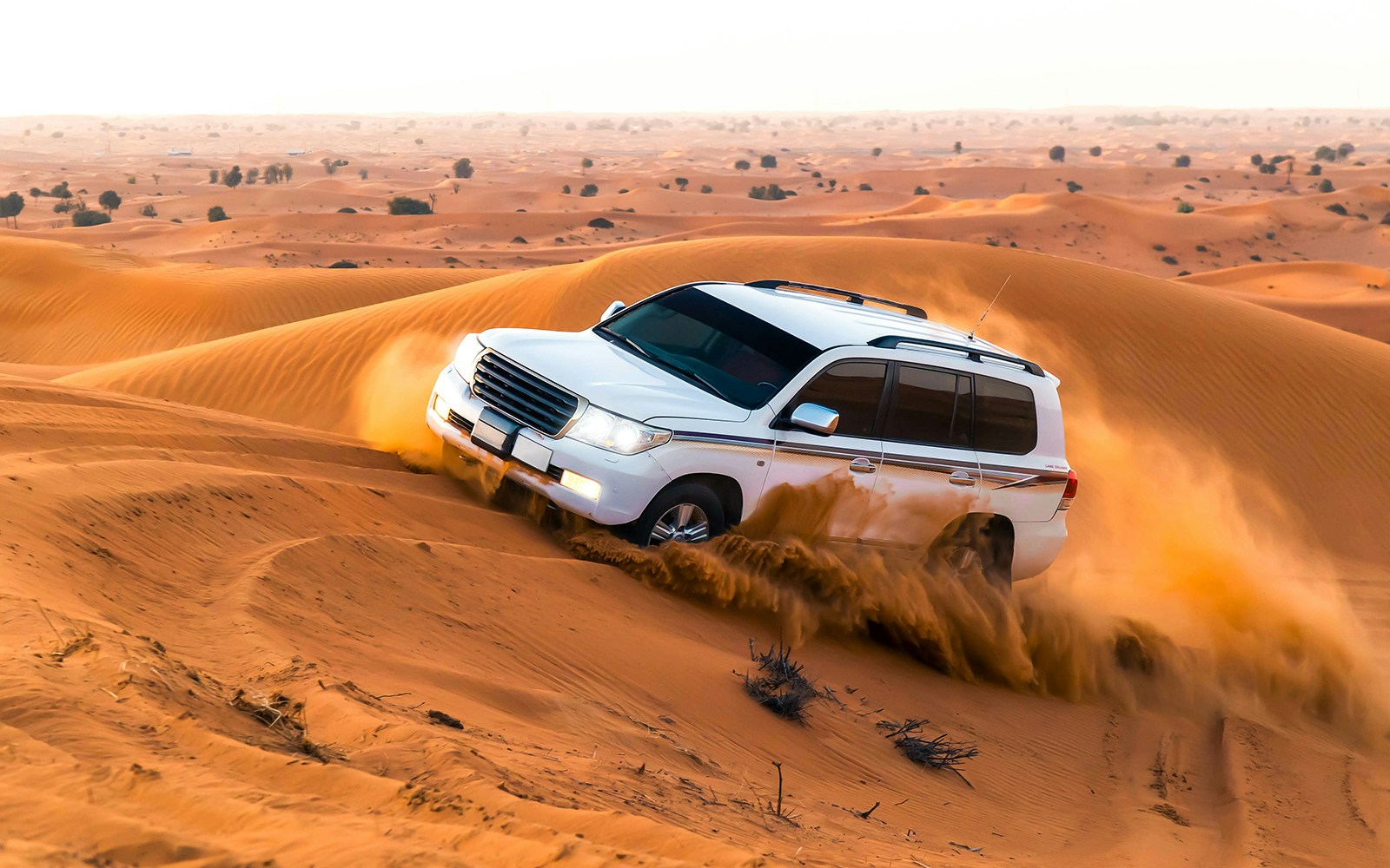 SUV driving through sand dunes during a desert safari in Dubai.