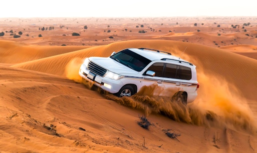 Dune bashing in a 4x4 vehicle on a desert safari, Dubai, with sand dunes in the background.
