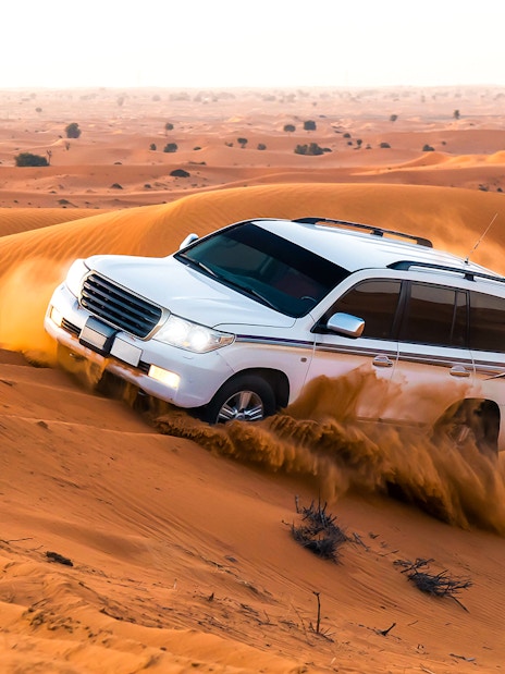 SUV driving through sand dunes during a desert safari in Dubai.