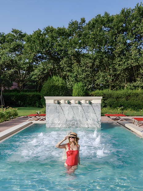 Visitor enjoying the pool at QC Terme Roma Resort & Spa, Italy, surrounded by greenery.