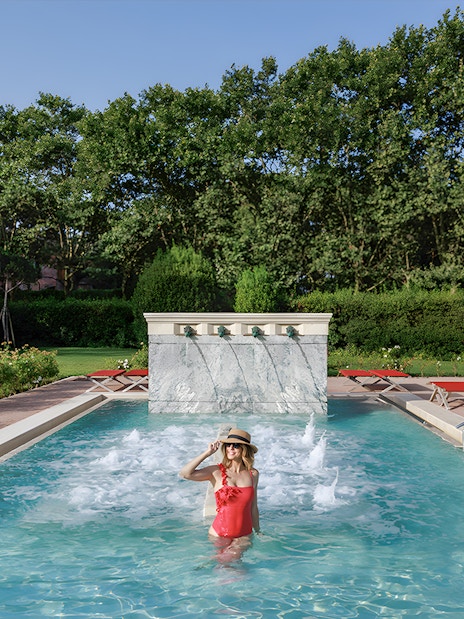 Visitor enjoying the pool at QC Terme Roma Resort & Spa, Italy, surrounded by greenery.