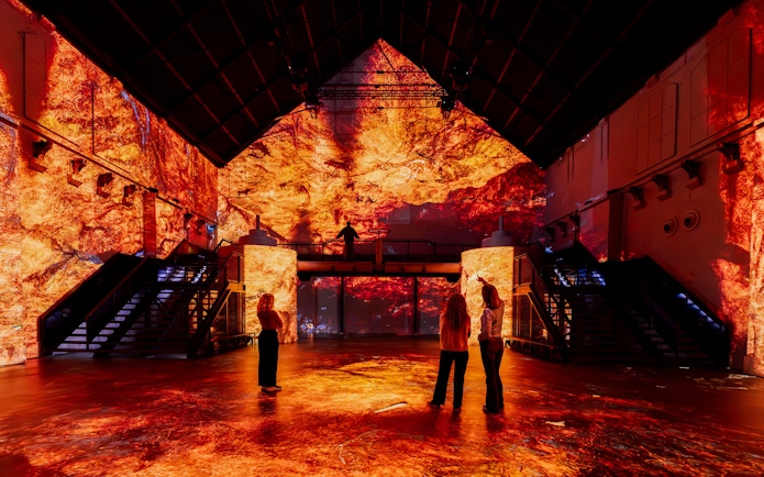 Immersive dinosaur-themed exhibit with fiery visuals at Prehistoric Planet experience.