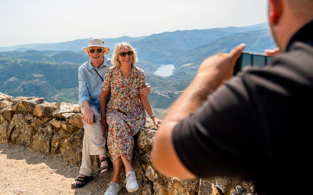 Tourists with guide taking photos of scenic mountain view in Douro valley