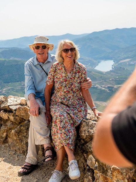 Tourists with guide taking photos of scenic mountain view in Douro valley