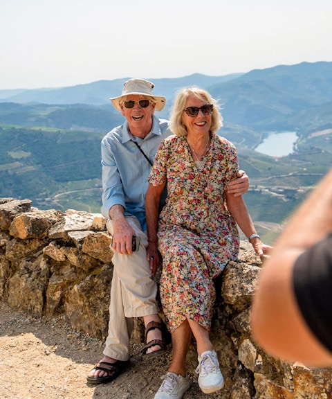 Tourists with guide taking photos of scenic mountain view in Douro valley