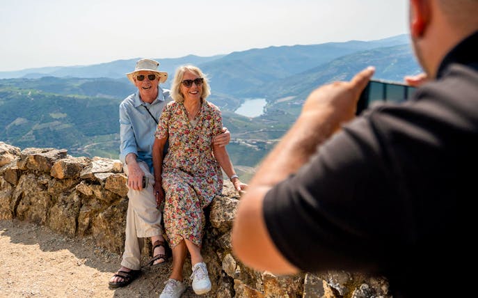 Tourists with guide taking photos of scenic mountain view in Douro valley