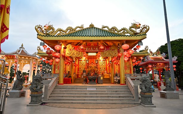 Chinese temple adorned with red lanterns and dragon motifs in Phuket during evening food tour.