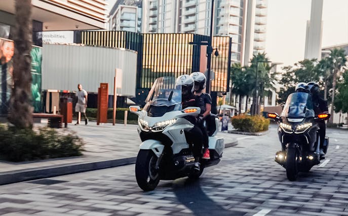 Motorcyclists riding through urban Dubai on a premium passenger tour.
