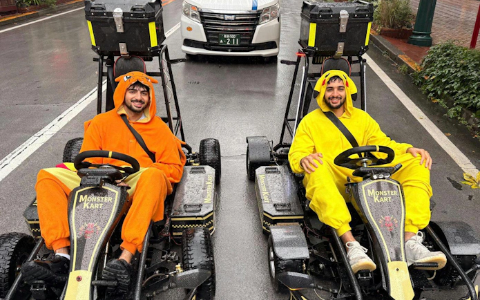 Two people in character costumes driving go-karts on a street during the Asakusa Electric Go Kart 120 min Tour.
