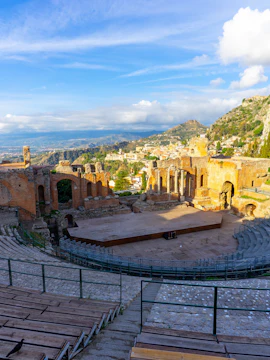 Ancient Greek Theater of Taormina in Sicily at sunrise with scenic mountain views.