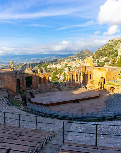 Ancient Greek Theater of Taormina in Sicily at sunrise with scenic mountain views.