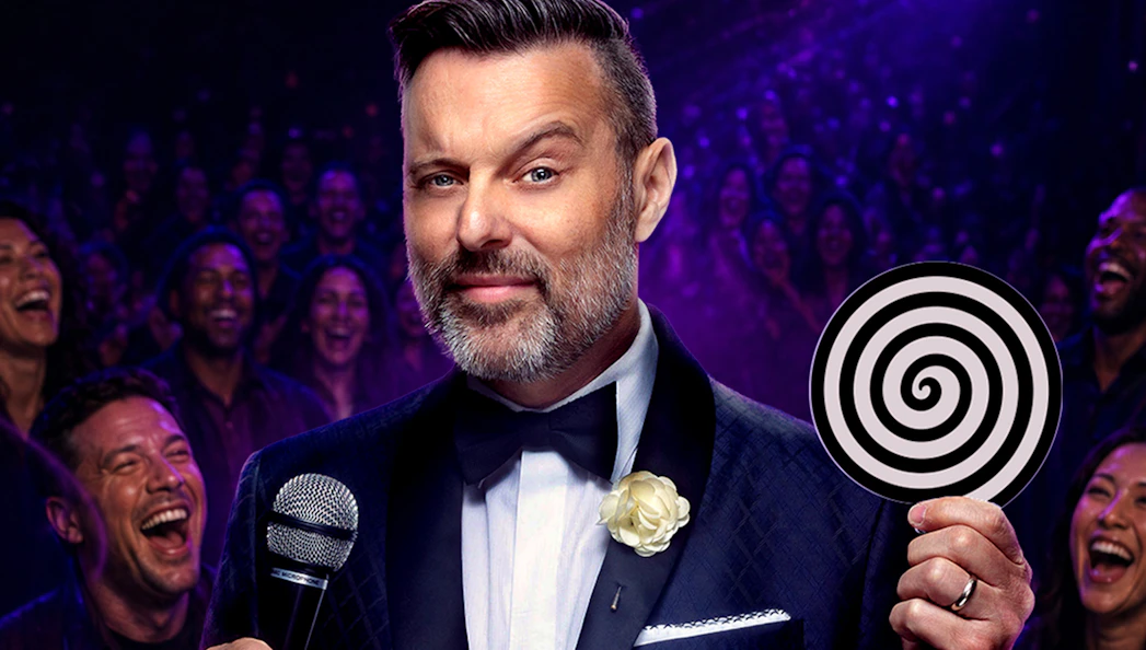 Hypnotist performing on stage with audience laughing, holding a spiral disc.