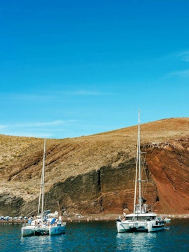 Catamaran cruise near the red beach cliffs in Santorini.