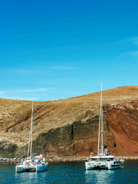 Catamaran cruise near the red beach cliffs in Santorini.