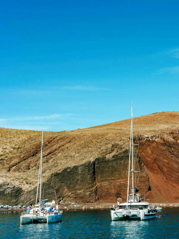Catamaran cruise near the red beach cliffs in Santorini.