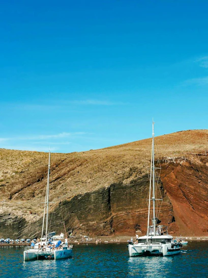 Catamaran cruise near the red beach cliffs in Santorini.