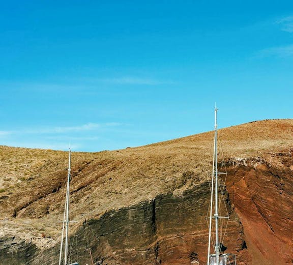 Catamaran cruise near the red beach cliffs in Santorini.