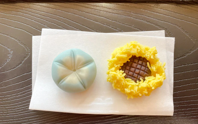 Japanese traditional sweets on a plate, featuring a blue wagashi and a yellow kinton.