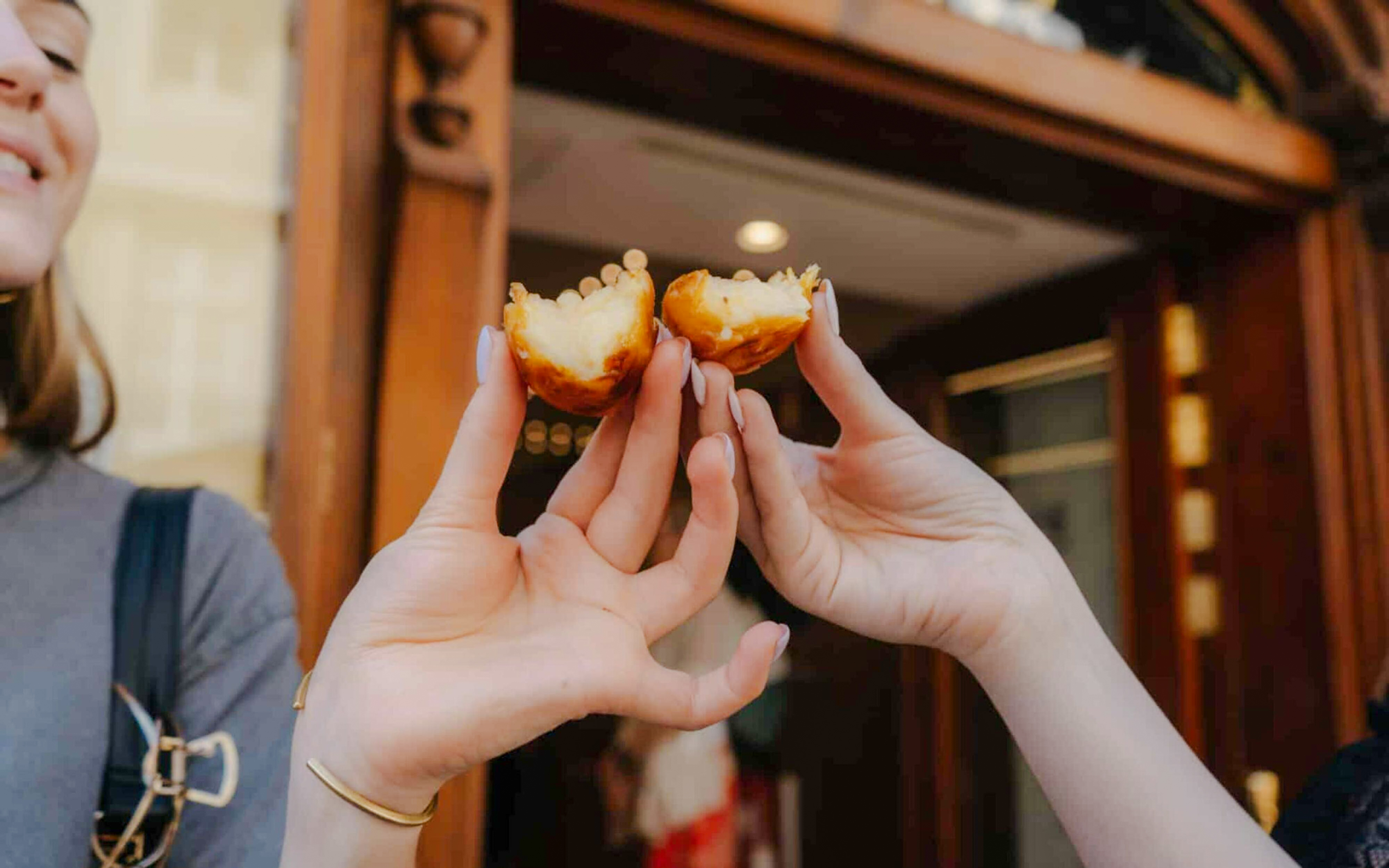Hands holding pastel de nata on Lisbon food tour.