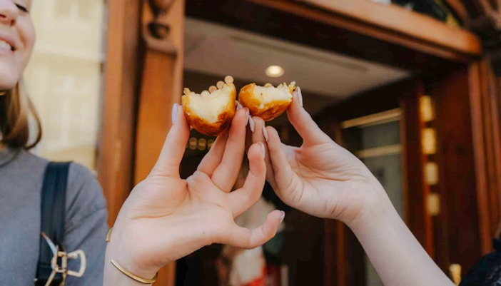 Hands holding pastel de nata on Lisbon food tour.